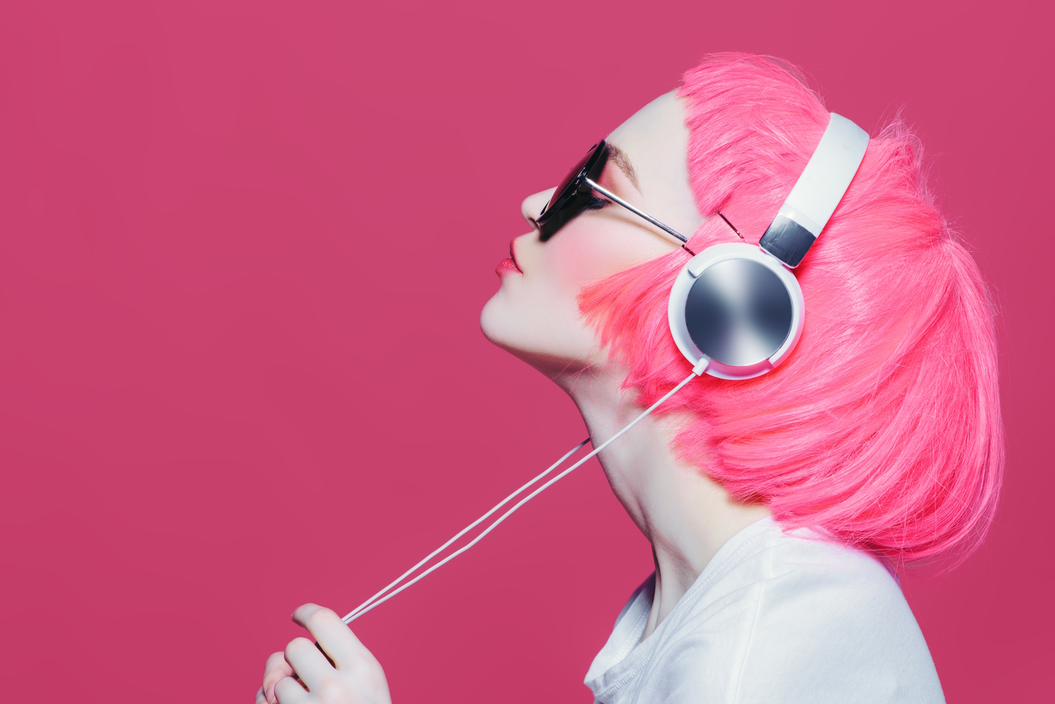 Chica con el pelo rosa escucha música con unos auriculares overear